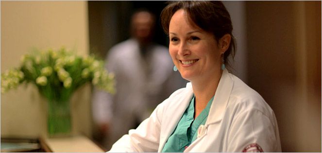 Physician in a lab coat sitting at the front desk.